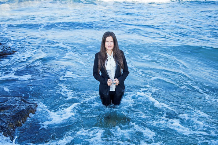 Inna Braverman wears a suit and stands knee-deep in the sea.