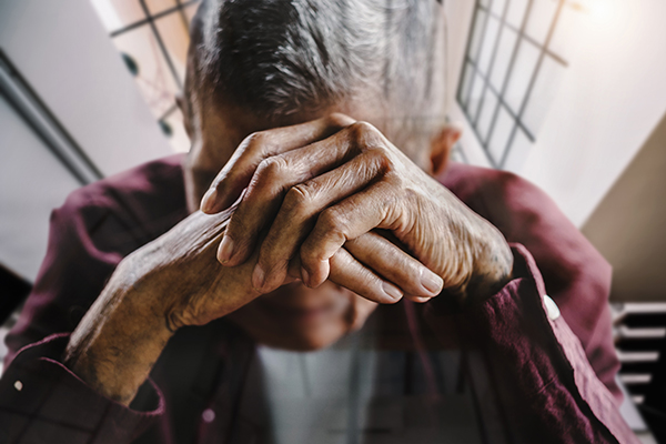 Un homme âgé se tient la tête dans ses mains