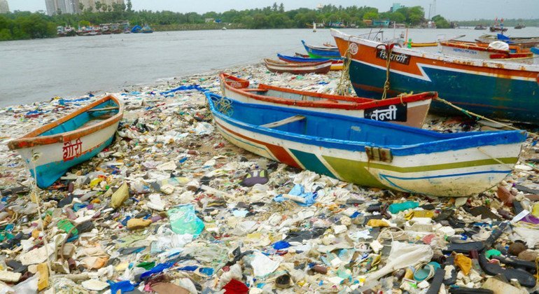 Des bateaux sur une plage recouverte de déchets plastiques