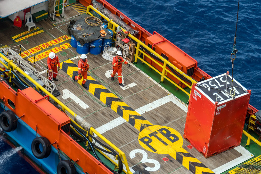 Workers on a ship with containers.