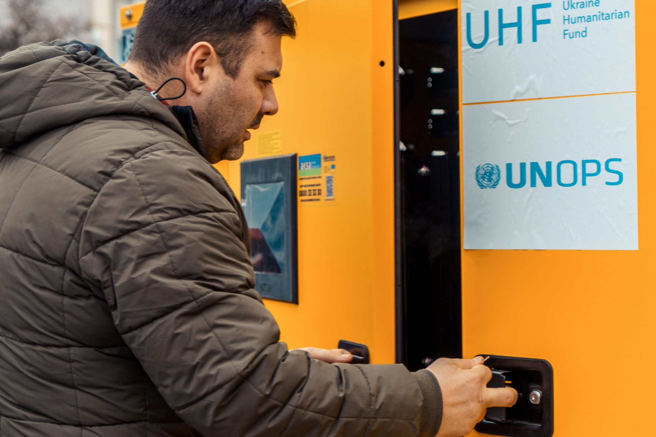 A man opening a door that reads: UNOPS Ukraine Humanitarian Fund