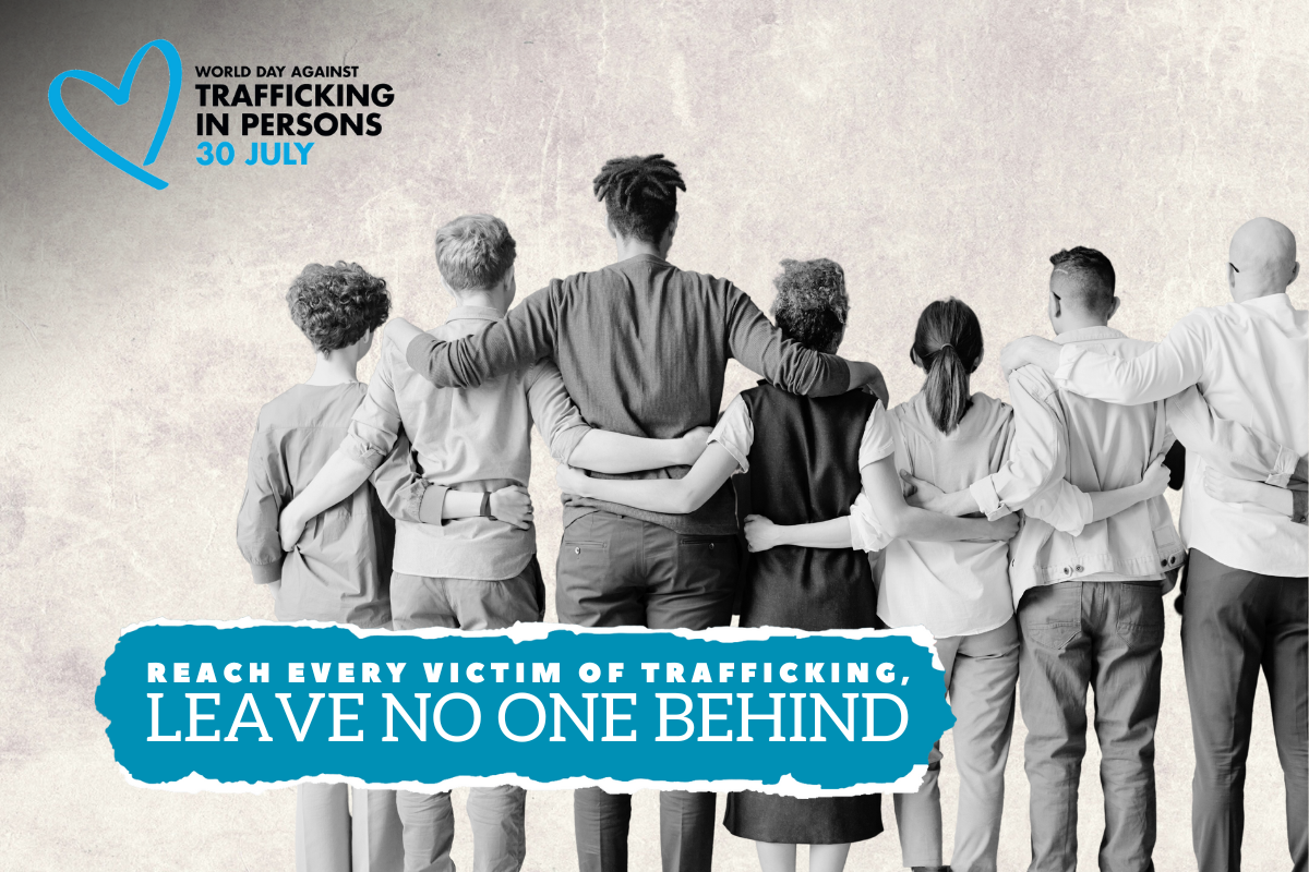 A black and white picture of people hugging with writing of the theme of the day: Reach every victim of trafficking, leave no one behind.
