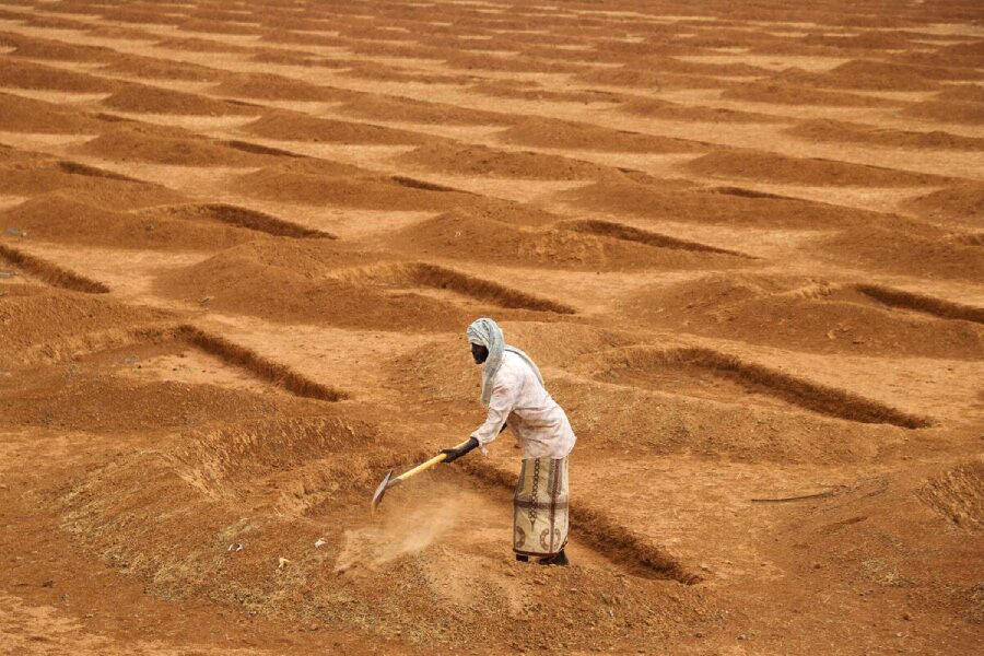 a farmer digs half-moons in a very arid terrain