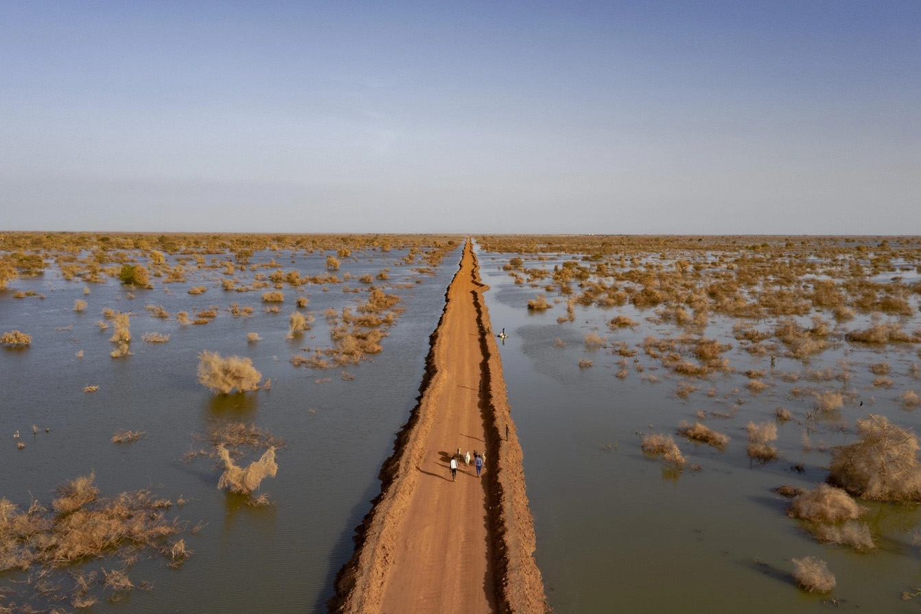 A dirt road along flooded plains seen from above