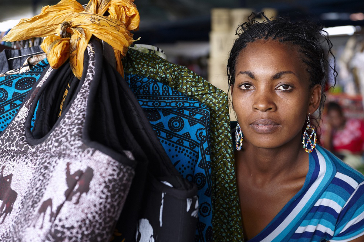 Une femme propriétaire d'une petite entreprise est assise à côté de ses marchandises dans un marché de rue.