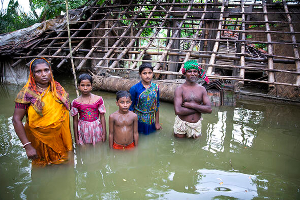 A family stands in waist-high floods outside their home.