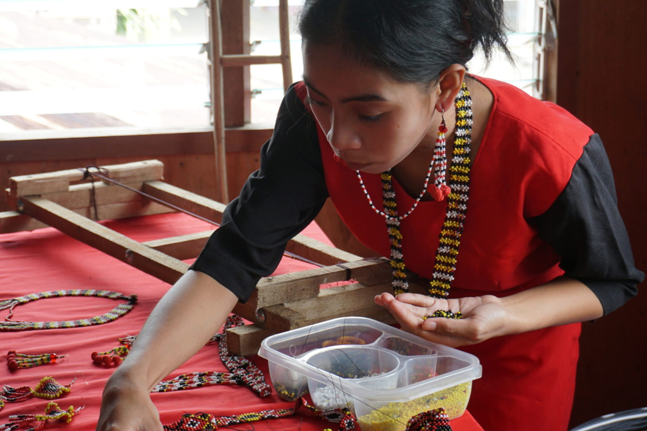 An indigenous woman working with beads.