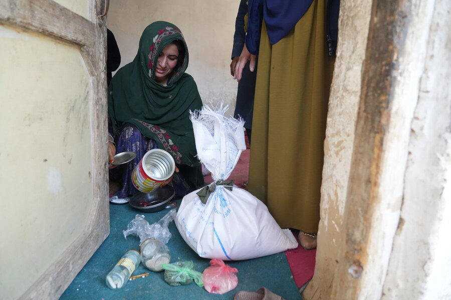 Une femme pleure devant des récipients alimentaires vides.