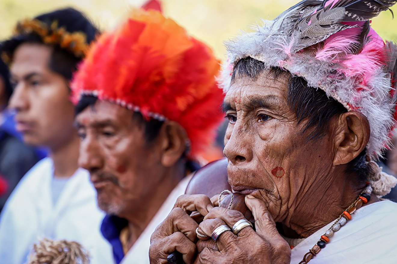 Trois personnes autochtones du Paraguay assistent à un événement.