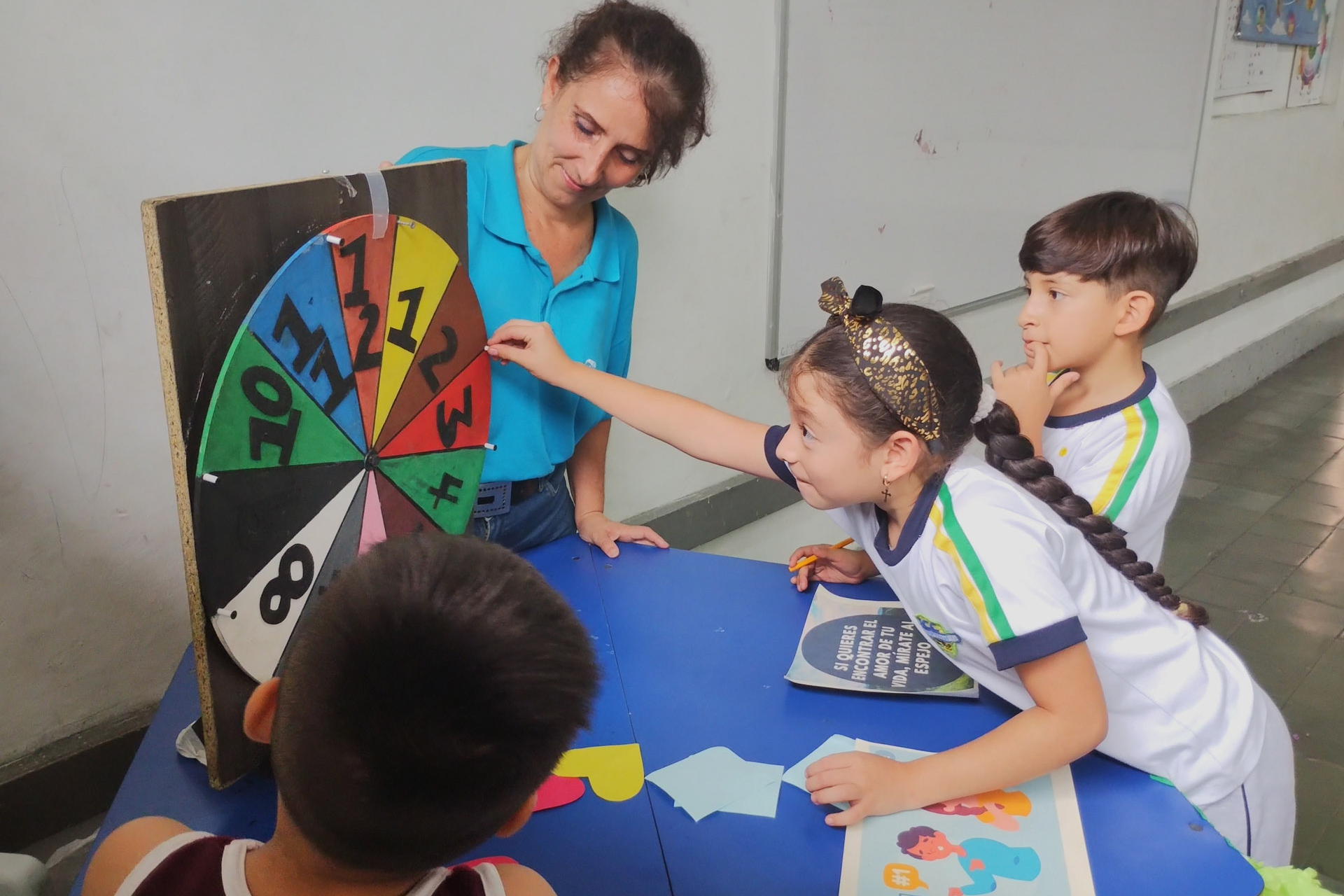 A lady playing spin the wheel with children.