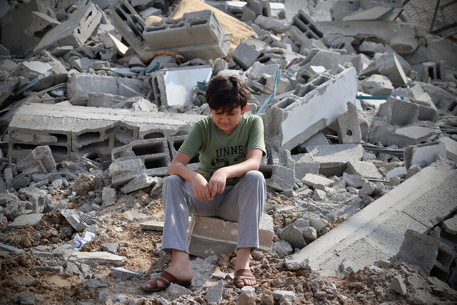 A young boy sitting in a pile of destruction.
