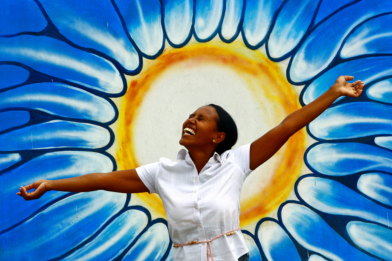 A cheerful woman in front of a graffiti celebrating World Mental Health Day.