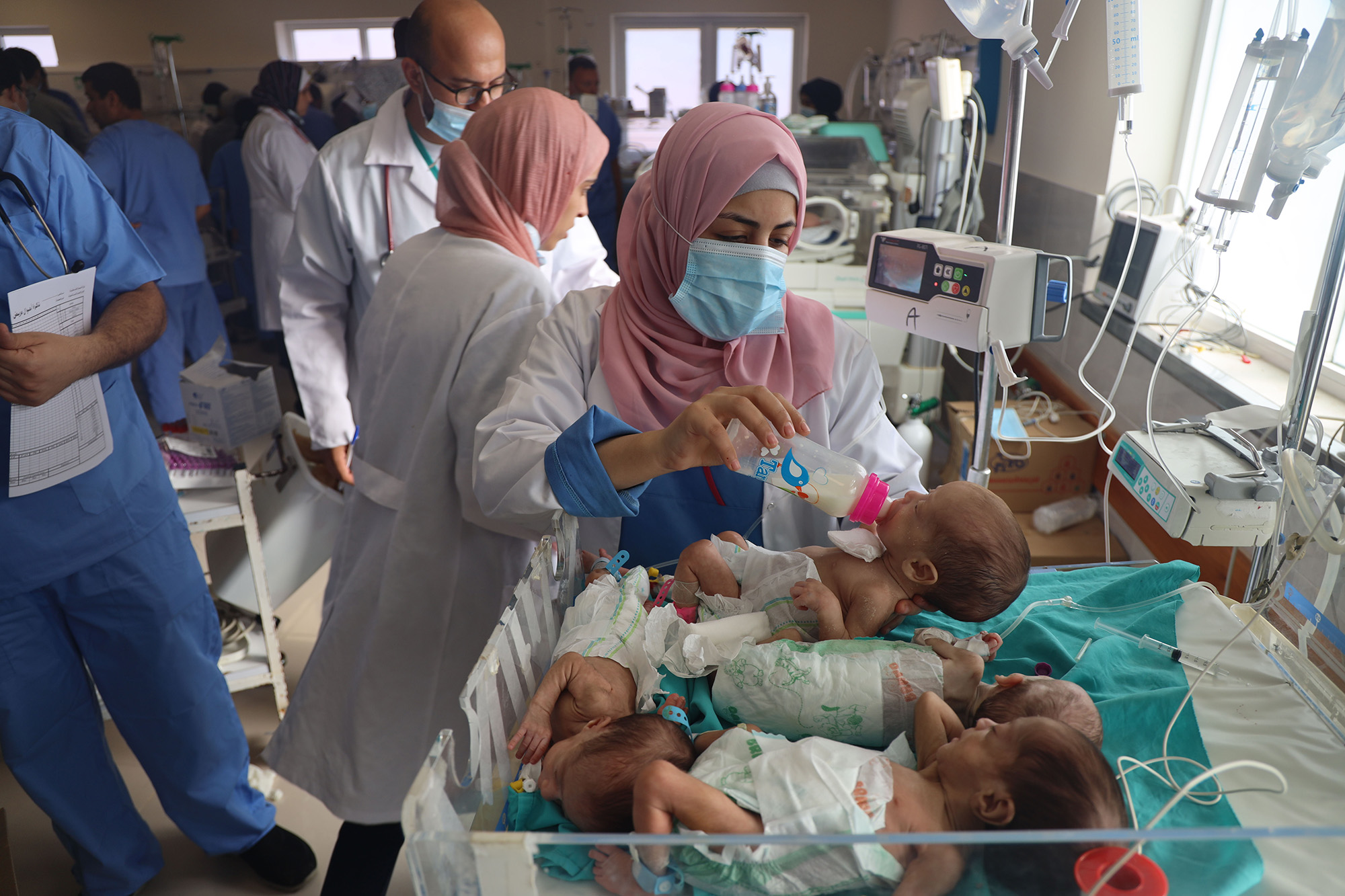 A nurse bottle-feeding a group of babies in a Gaza hospital.