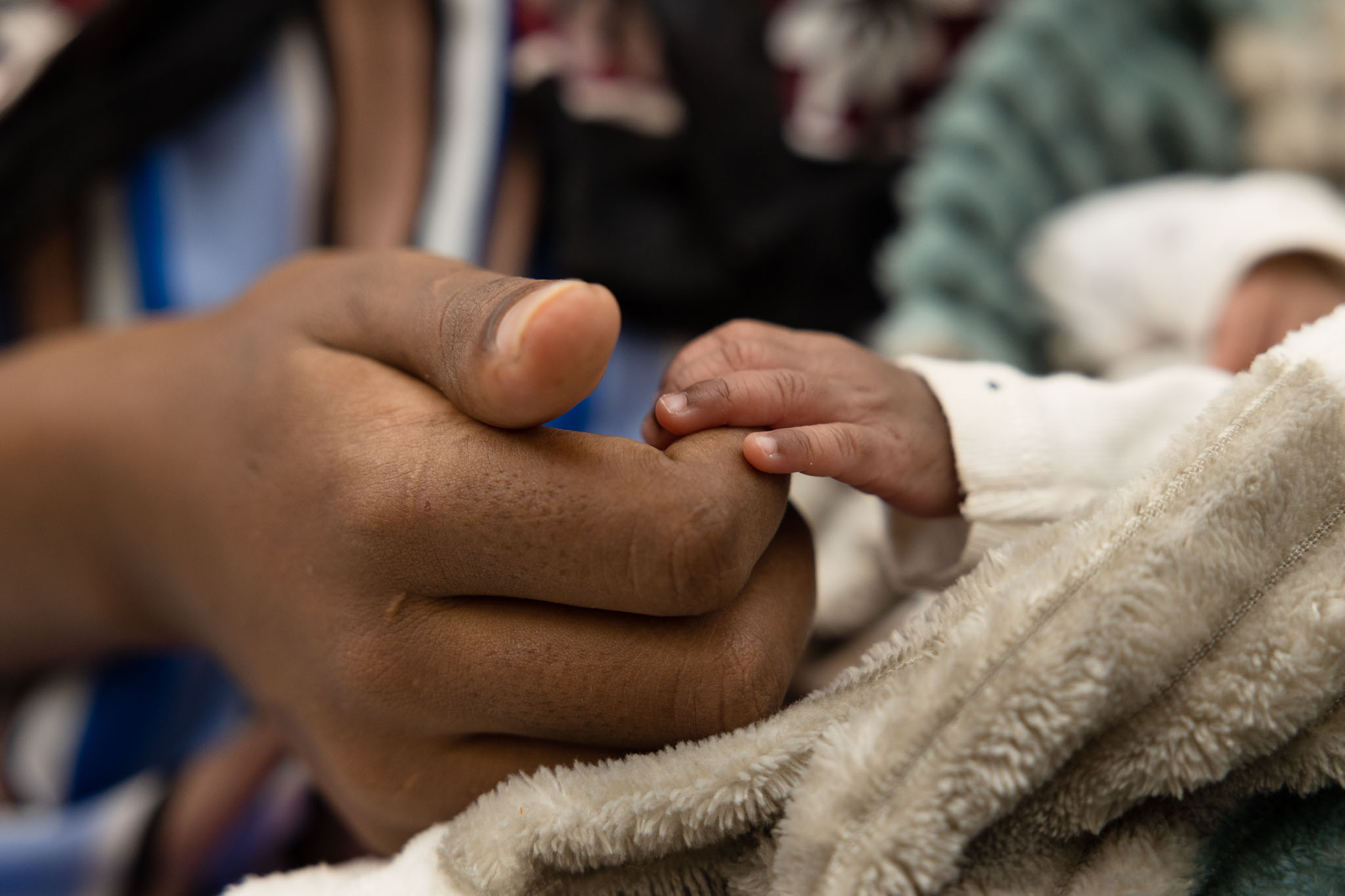 Une jeune femme tenant la main de son nouveau-né.