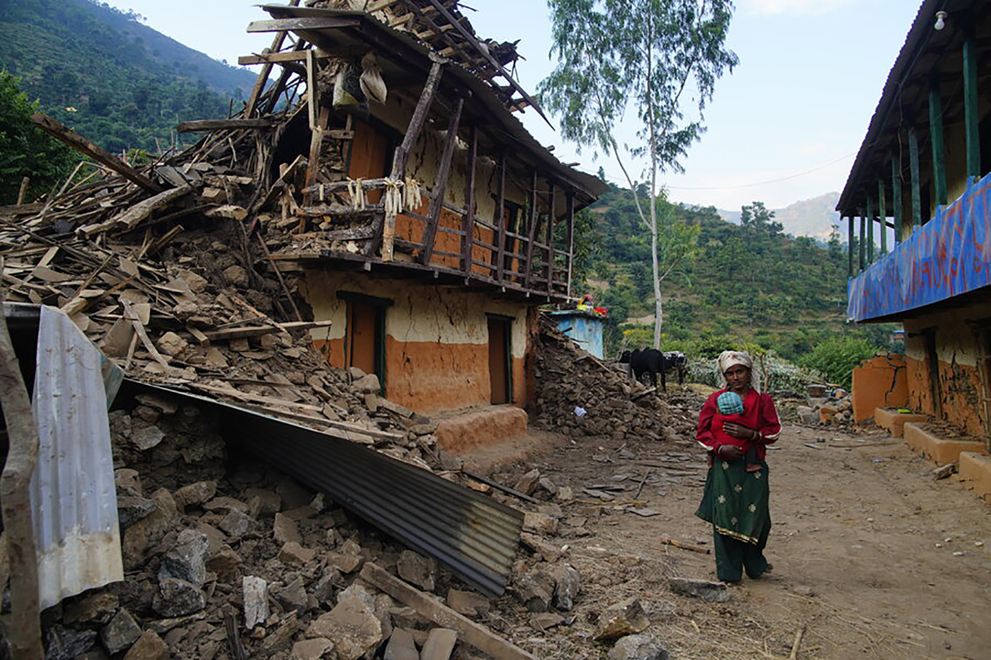 Two Nepal earthquake survivors walking past a house destroyed by the quake.