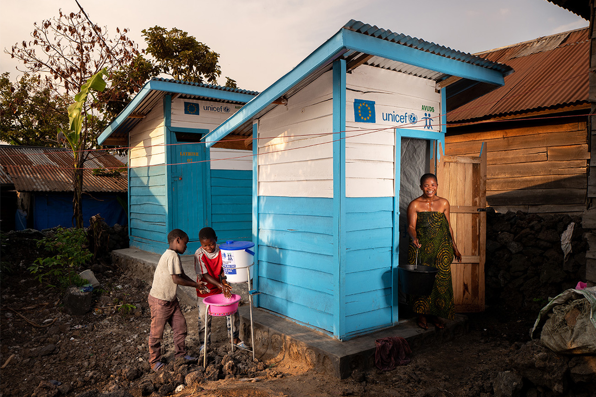 A woman getting out from a UNICEF´s latrine installation and two kids washing their hands next to it.
