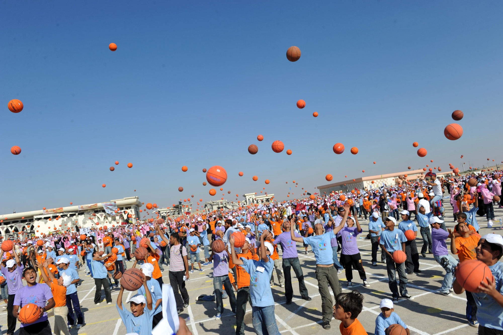 large group of children throwing basketballs into the air