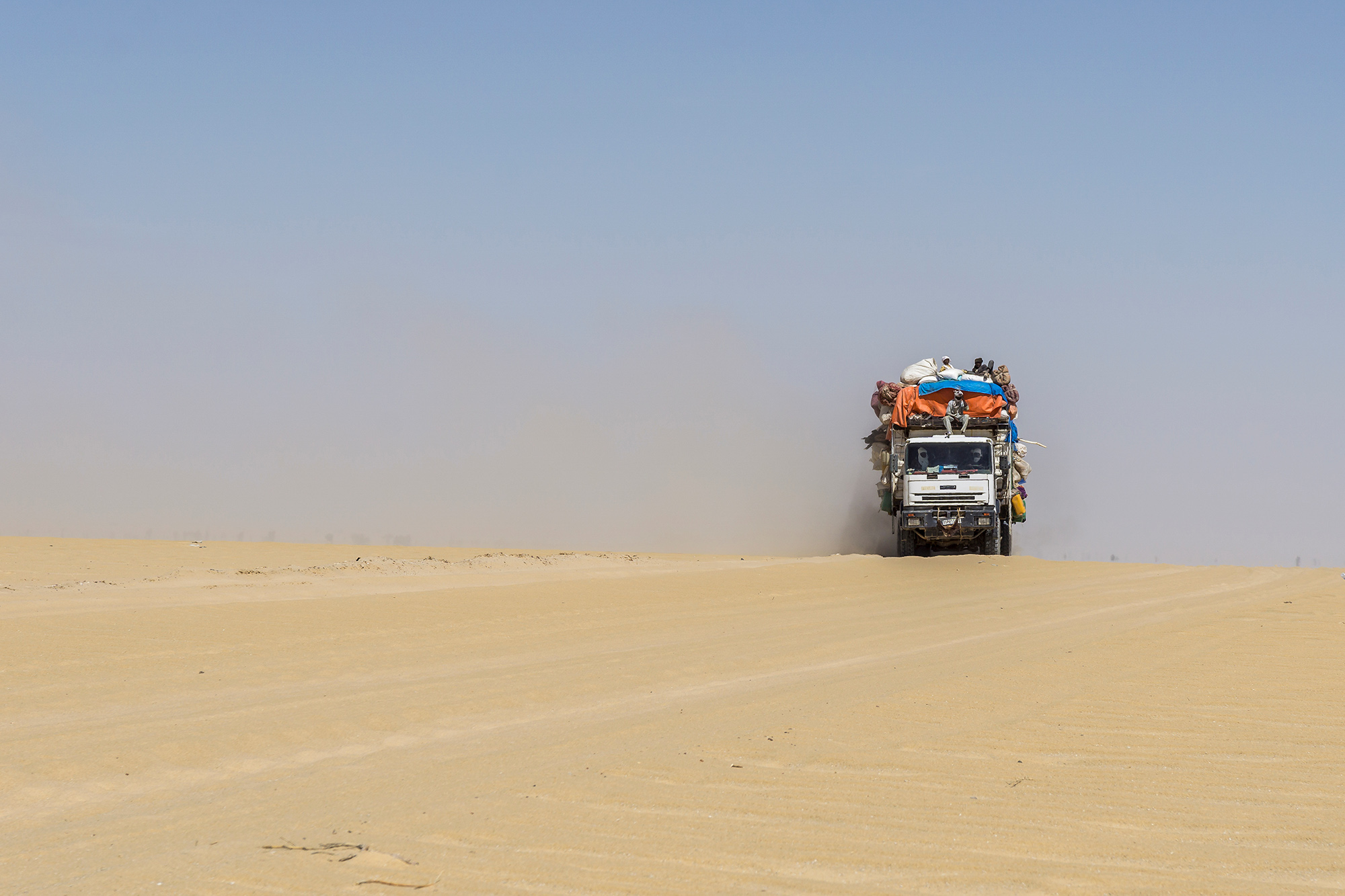 Heavily loaded truck transporting goods and people in the Sahara Desert, Chad.