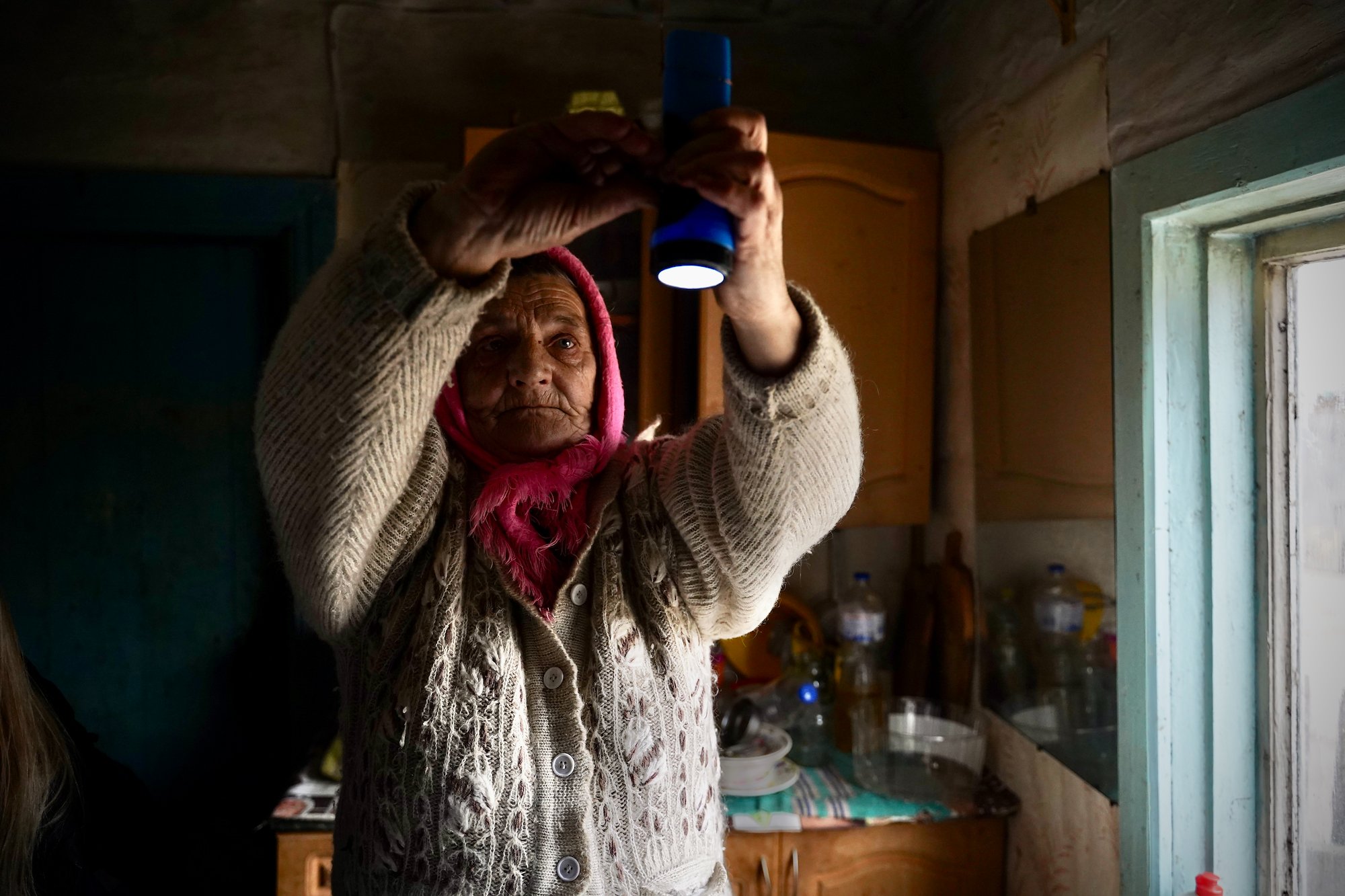 A Ukrainian woman hangs a lantern from the ceiling to use as a lamp in case of a power outage.