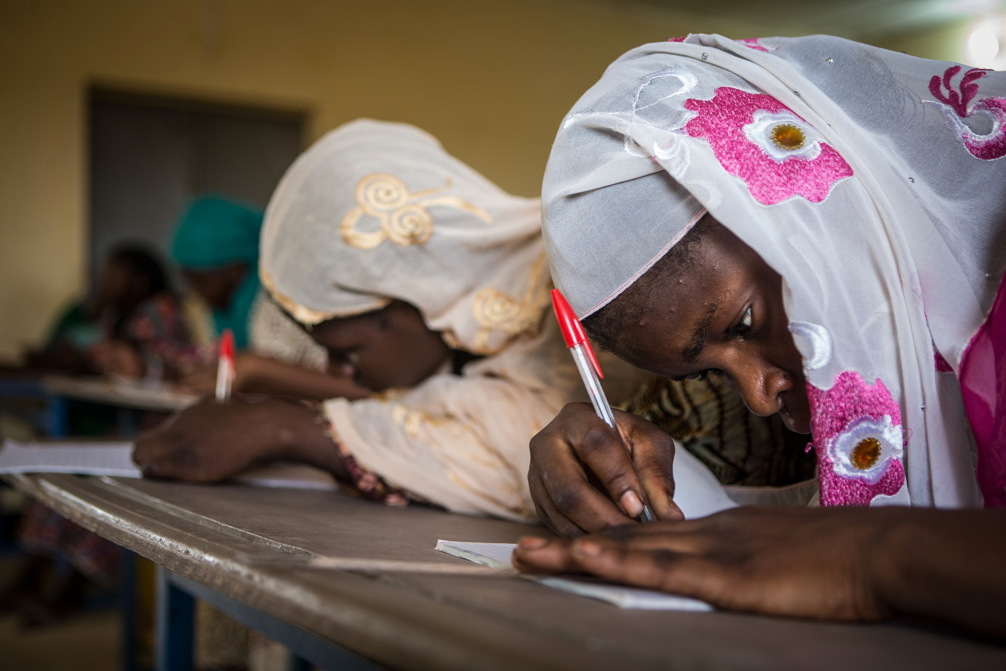 Two women writing on their desks during a literacy class in Mali.