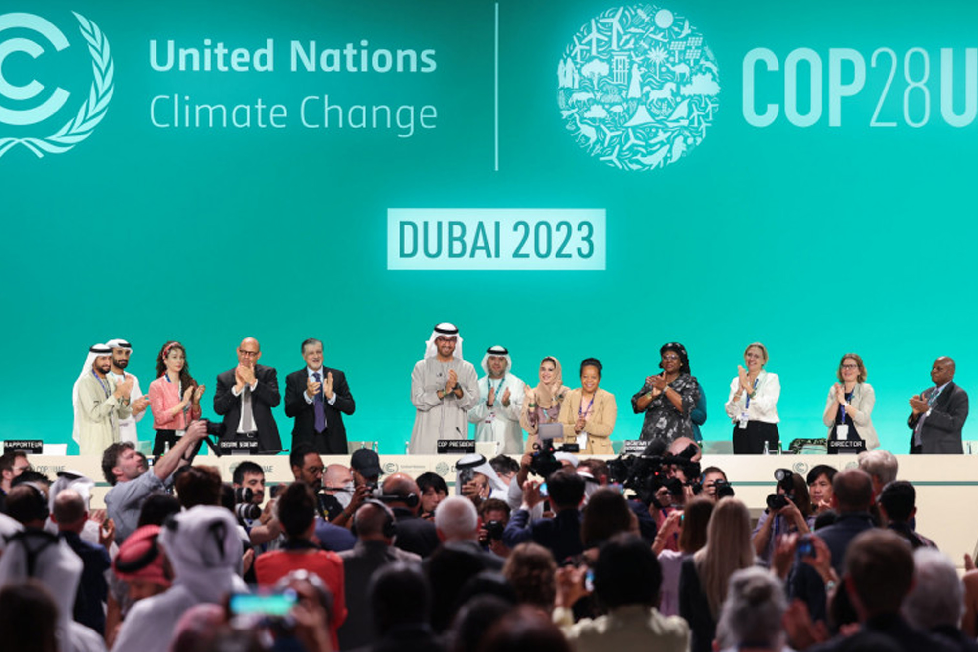 COP28 attendees applauding after reaching an agreement to move away from fossil fuels.