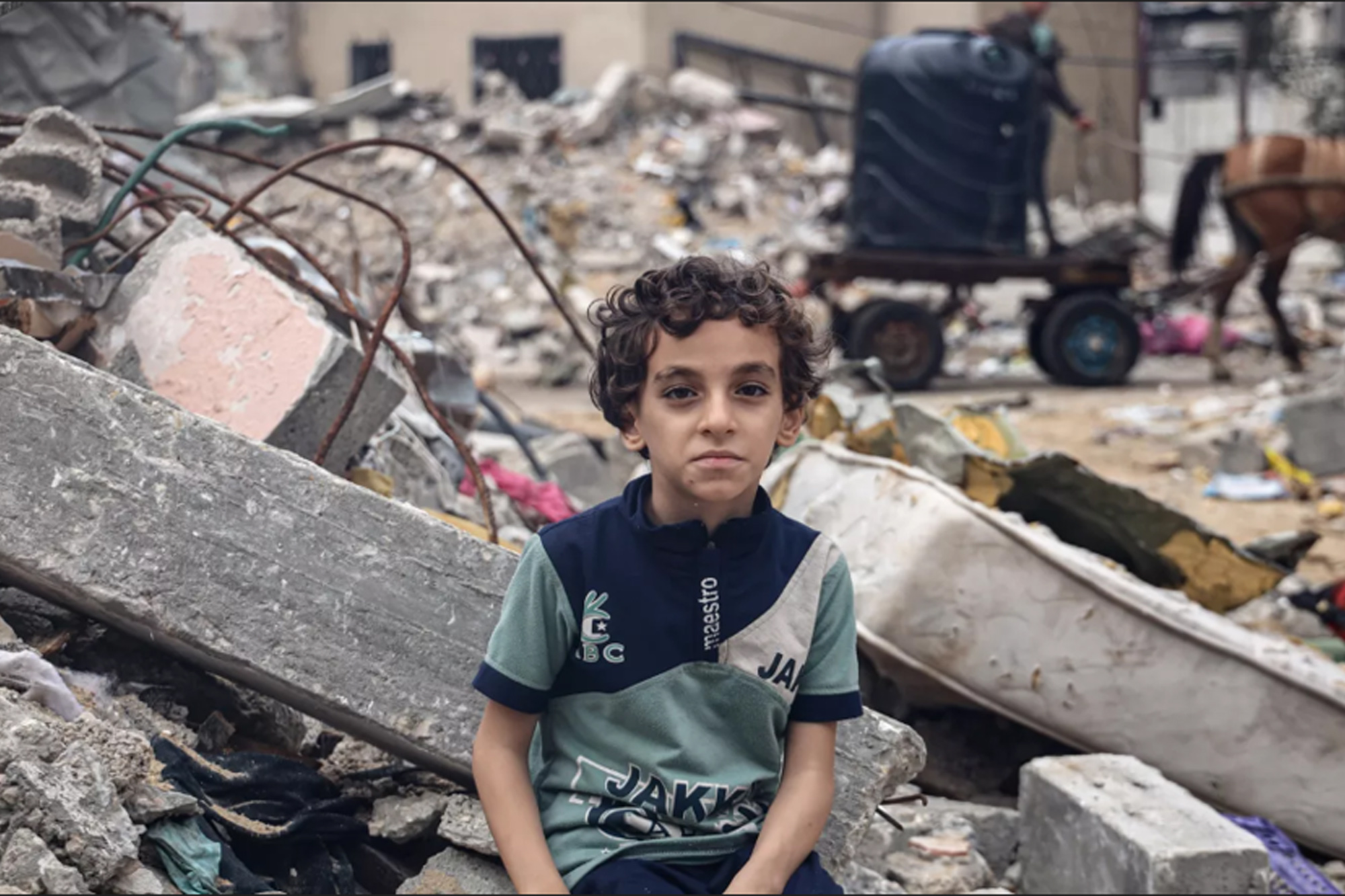 An 8-year-old Palestinian boy sits in the rubble of destroyed buildings in the Gaza Strip.