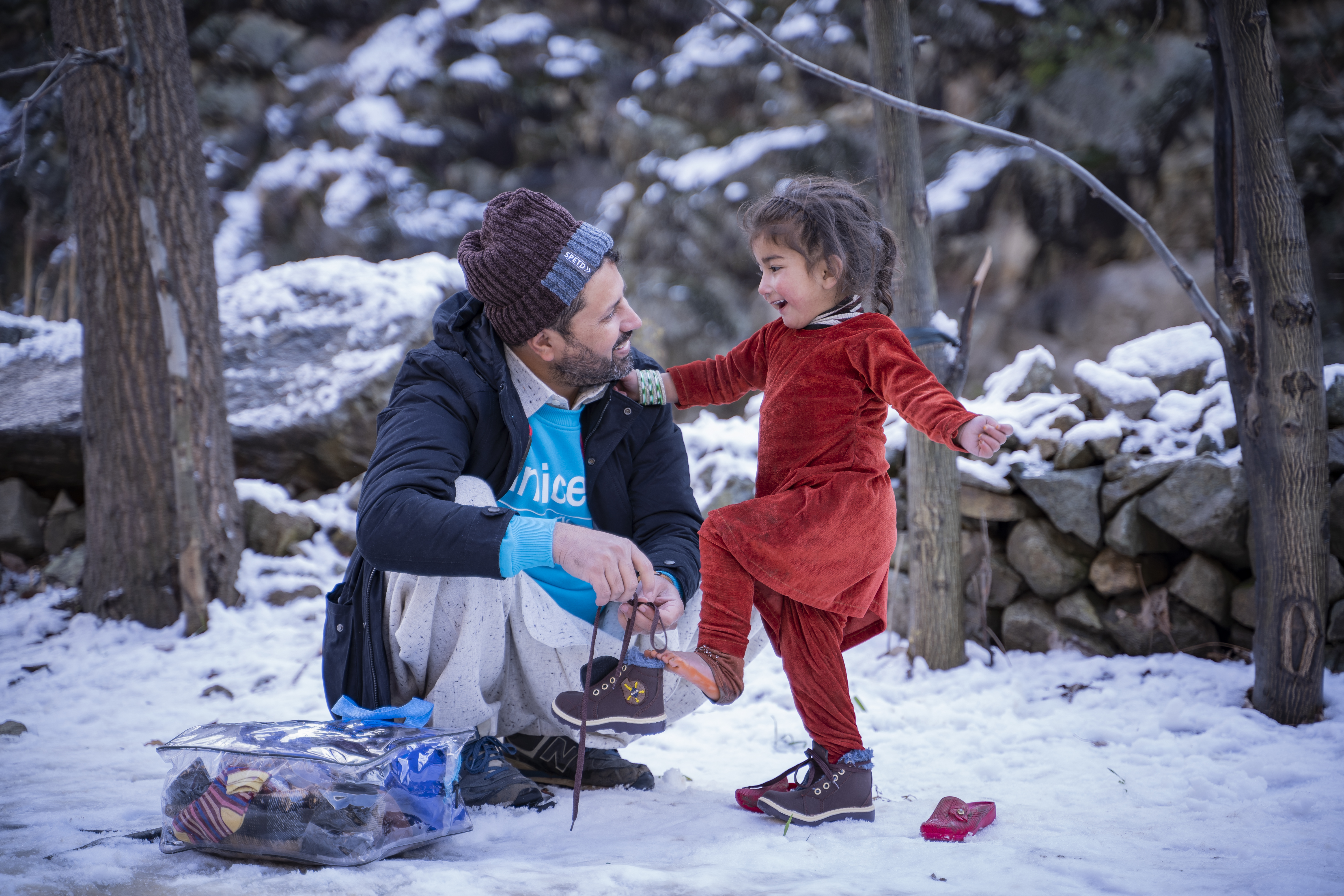 Dans le village de Sulool Daramdala (province de Khyber Pakhtunkhwa), un membre du personnel de l’UNICEF au Pakistan aide Muskan, 3 ans, à enfiler les nouvelles chaussures qu’elle a reçues dans le kit d’hiver distribué par l’UNICEF.