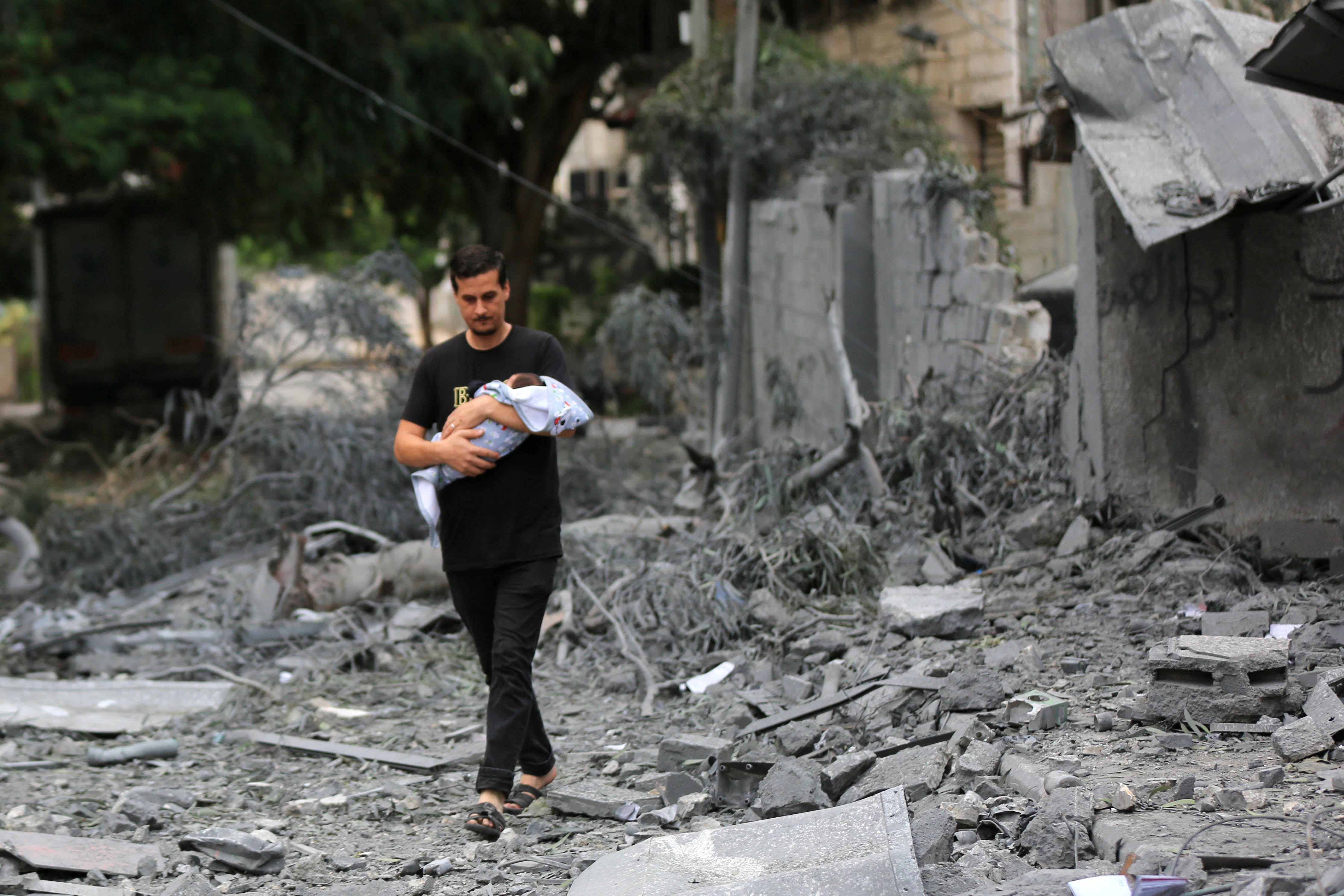A man carrying an infant through the rumble of destruction in Gaza.