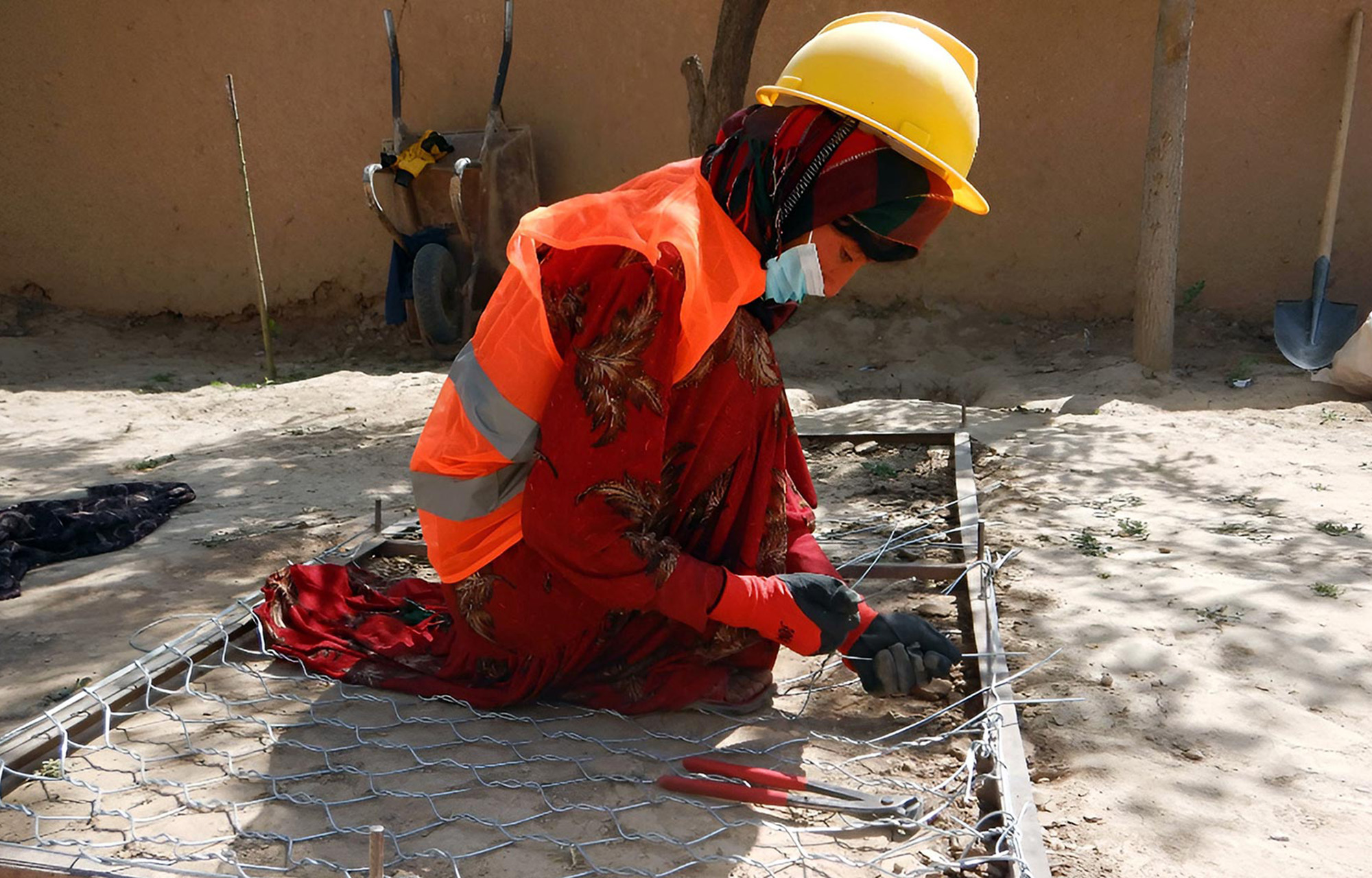 A woman weaves the wire mesh that holds together the stones that protect her ancient village from flash floods and soil erosion.