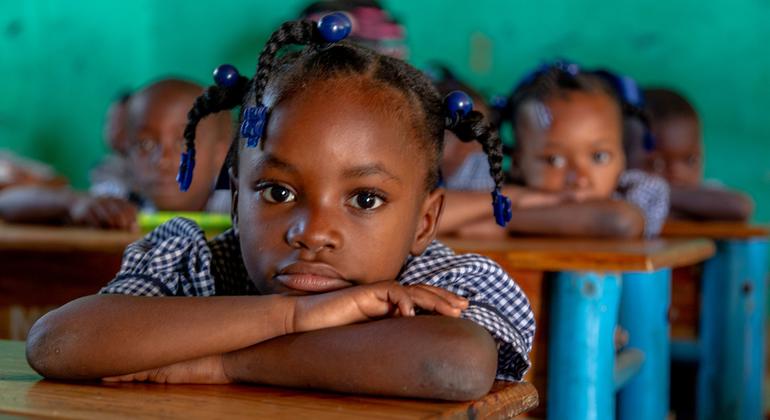 Une petite fille la tête posée sur ses bras croisés sur une table dans une salle de classe