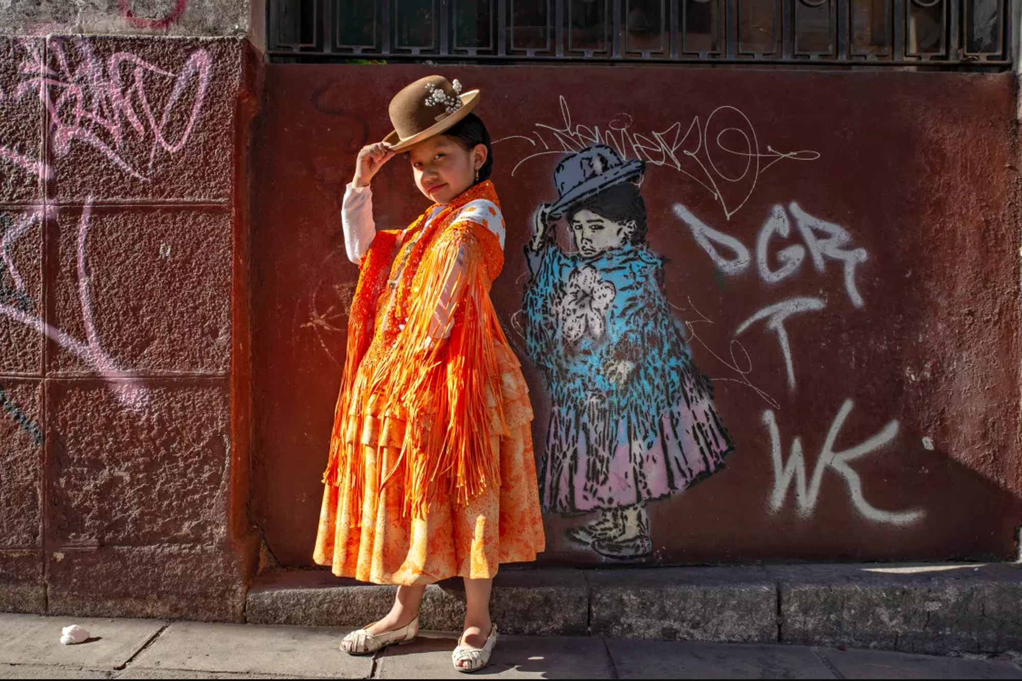 A 7-year-old Peruvian girl poses next to graffiti inspired by a photograph of her taken when she was 2 years old.