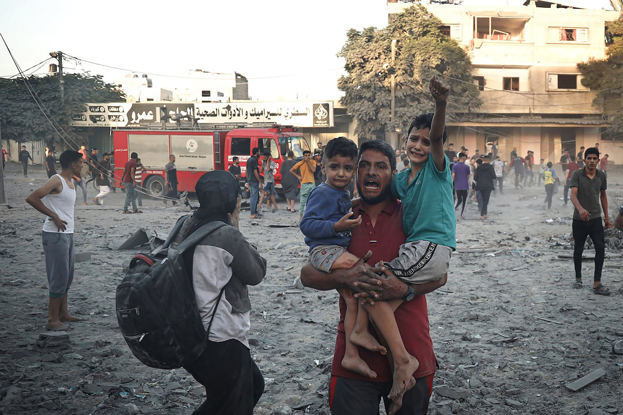 A man carrying his two children among the ruins inflicted by airstrikes on the city of Rafah.