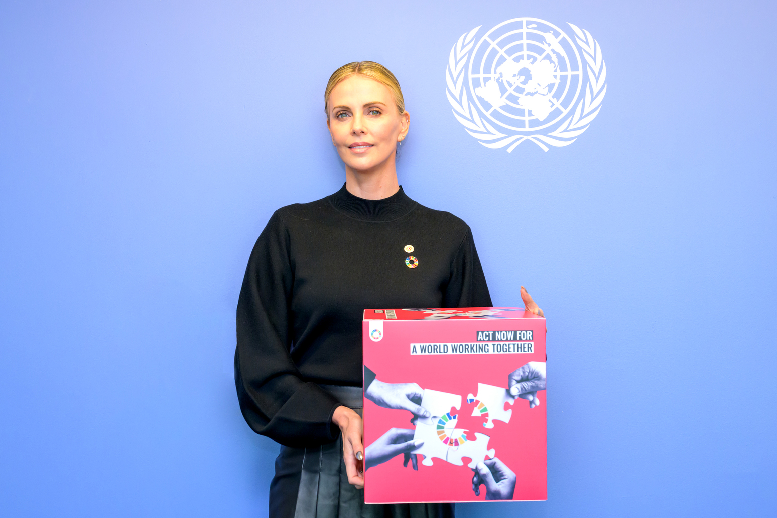 Charlize Theron holding sign with puzzle pieces
