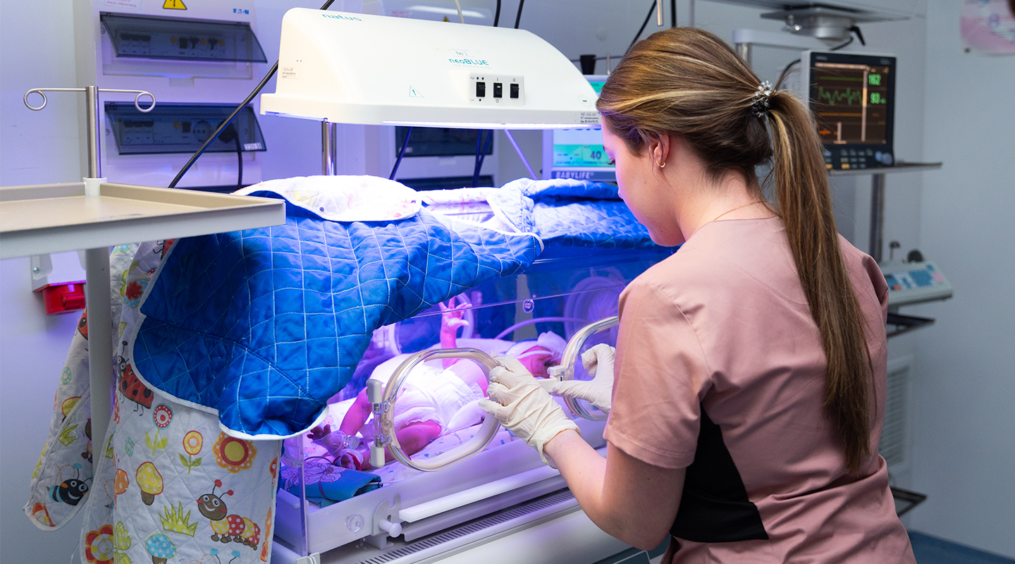 A nurse taking care of a baby placed inside an incubator.