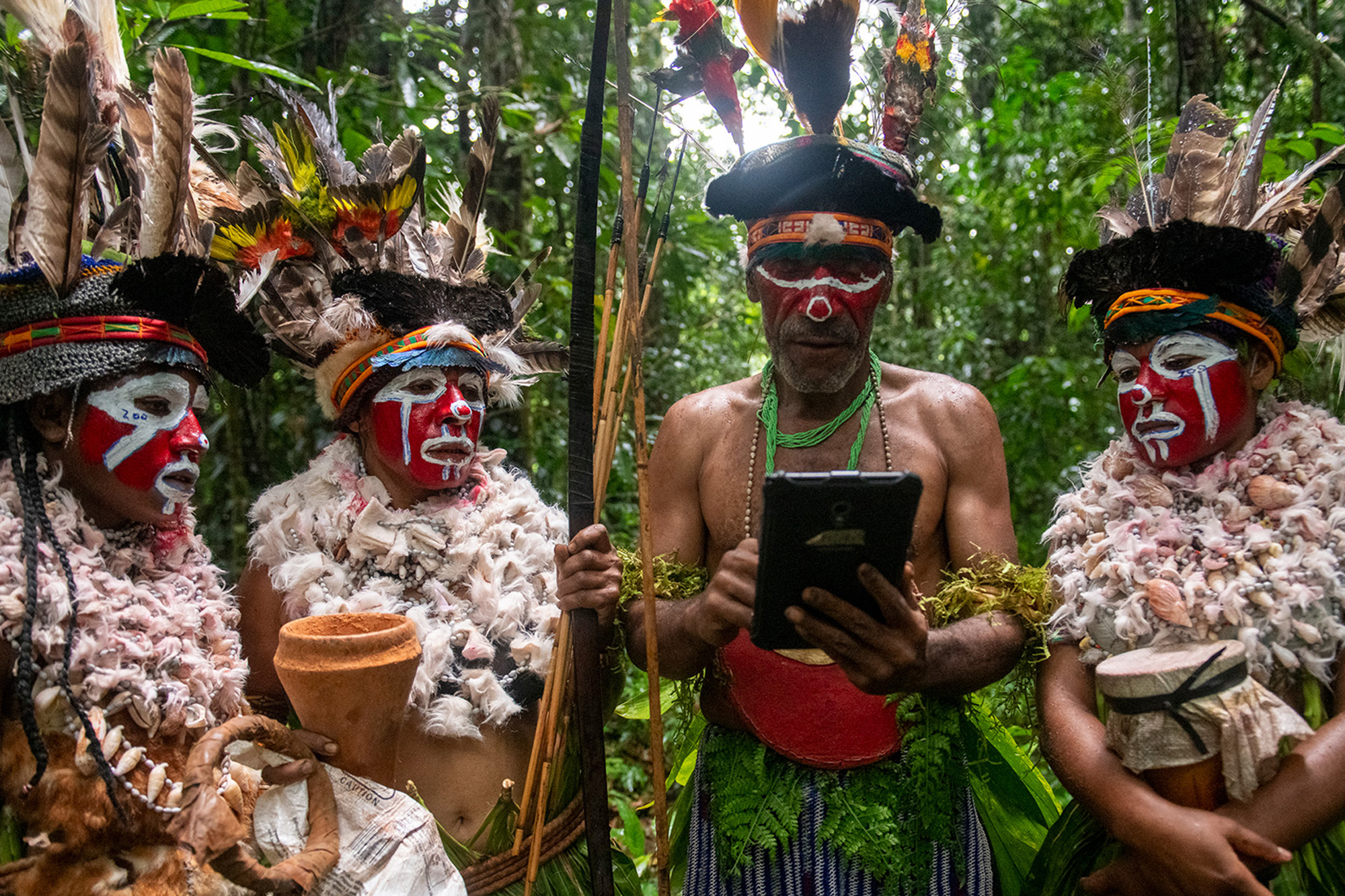 A group of indigenous people using a tablet to check information about the forest.