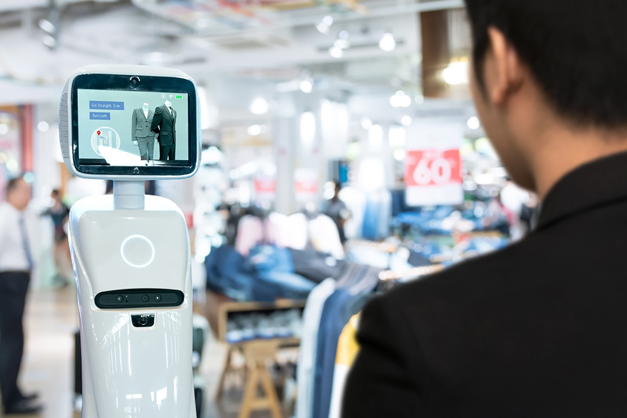 Un homme interagit avec un robot dans un centre commercial.