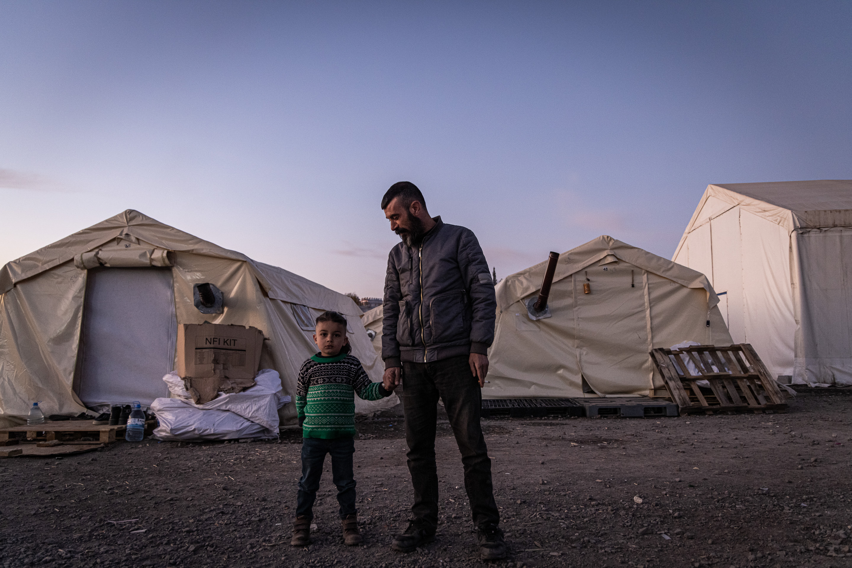 Un père tient son enfant par la main dans un camp de réfugiés