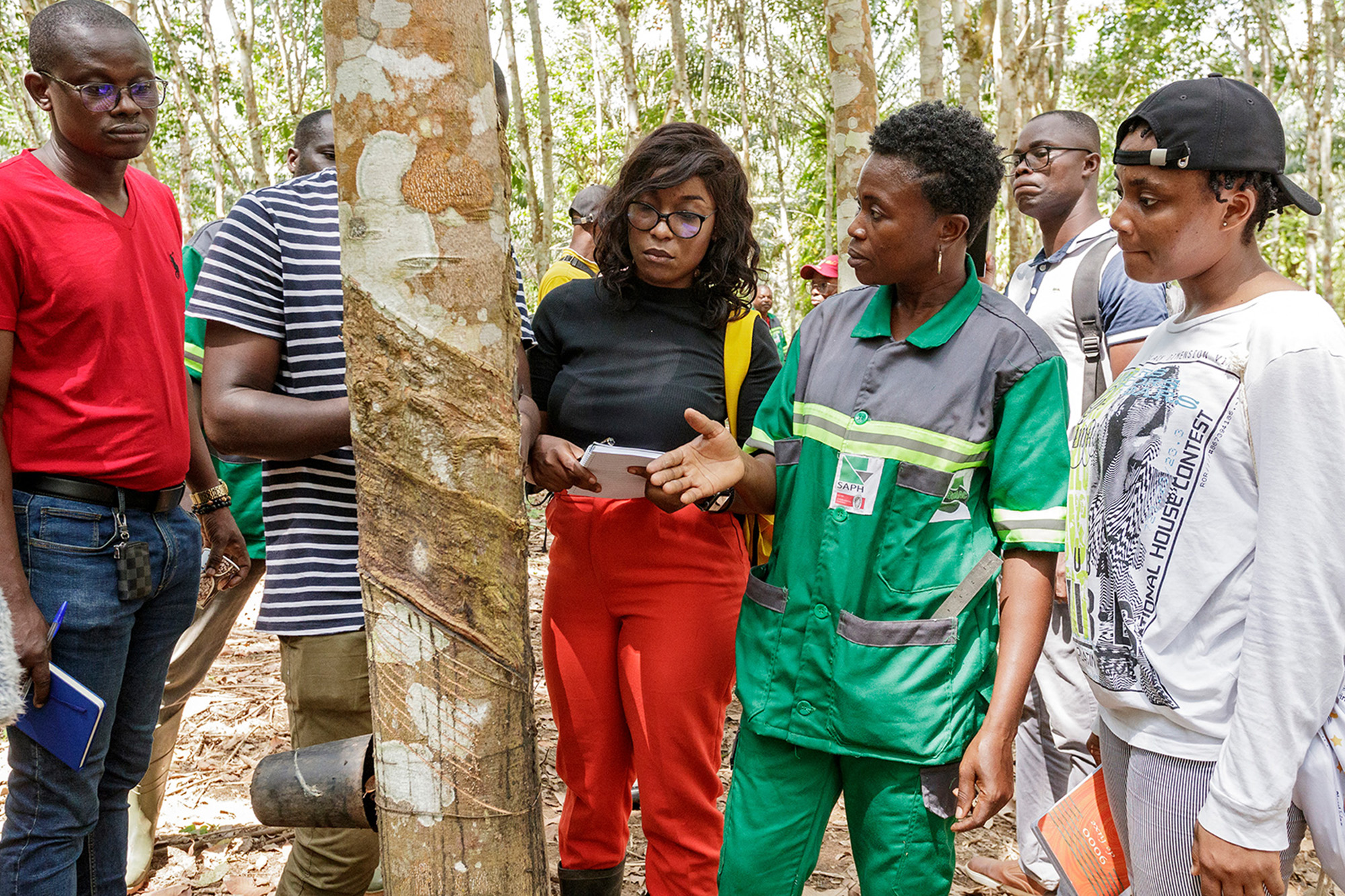 Une femme devant un arbre enseignant des pratiques durables à un groupe d'étudiants d'un programme de maîtrise en statistiques agricoles.
