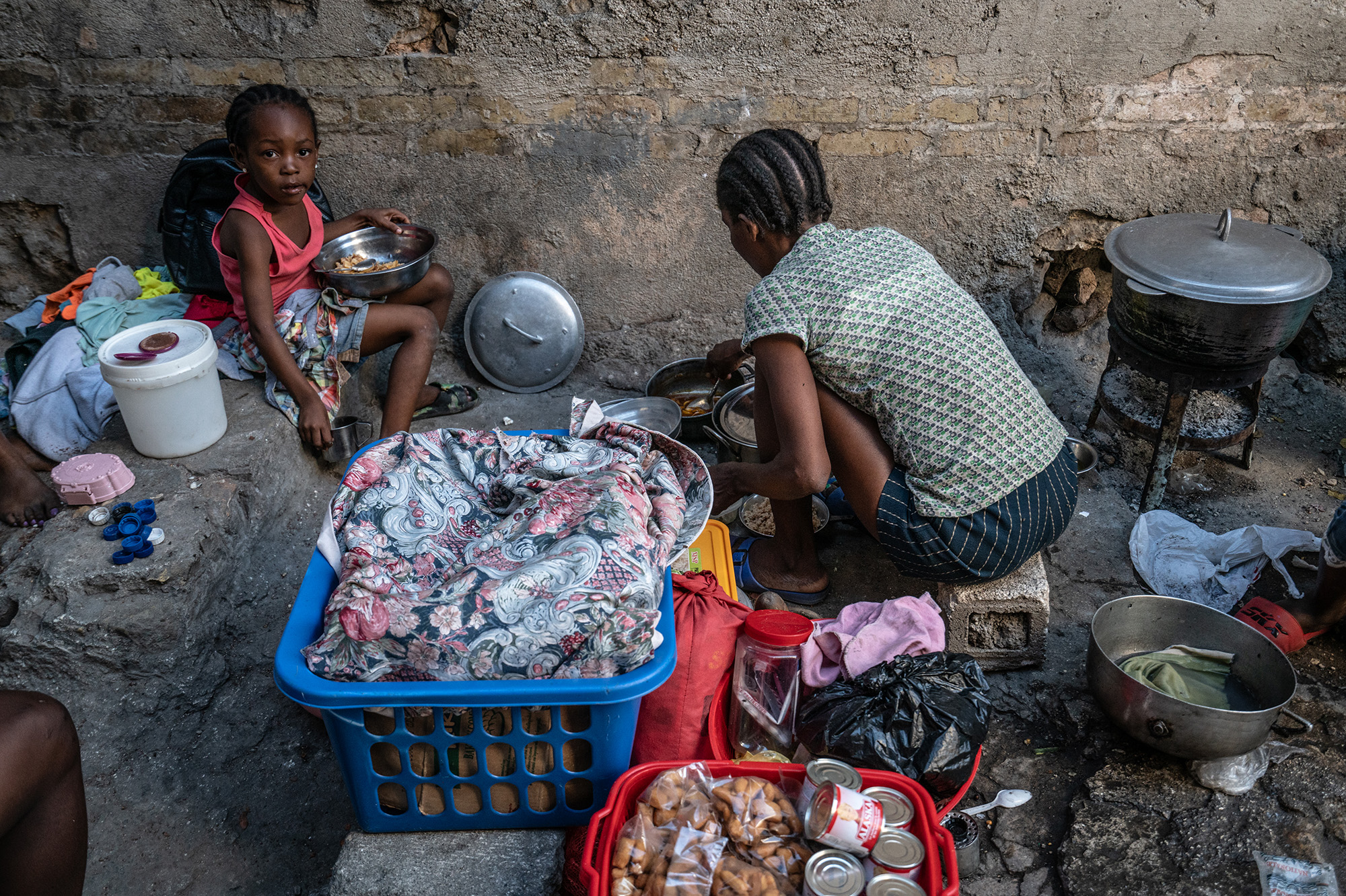 A displaced woman and a child preparing food inside a theatre in downtown Port-au-Prince.