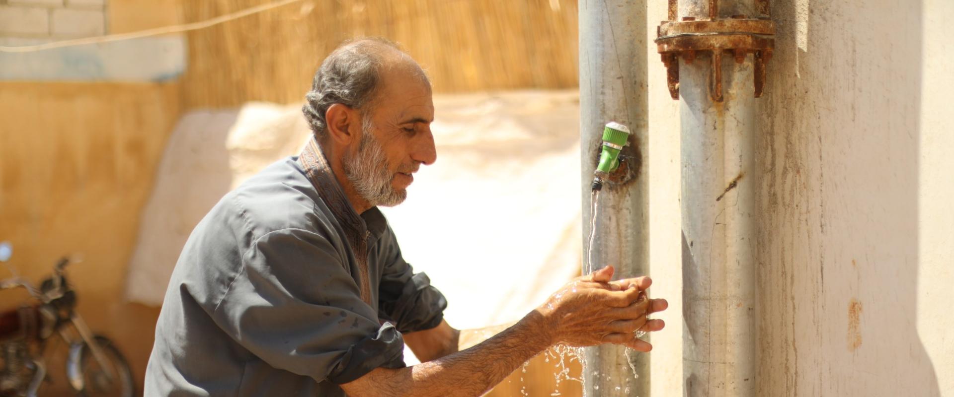 A man washes his hands in a northwest Syria camp.