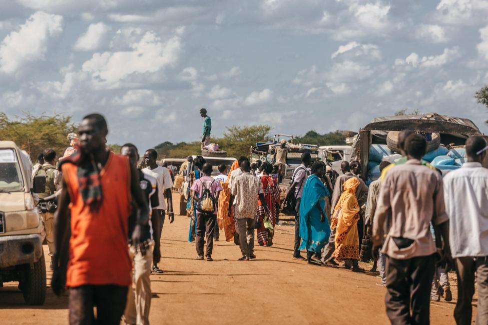 De nombreuses personnes marchent au milieu de voitures dans une rue en Afrique