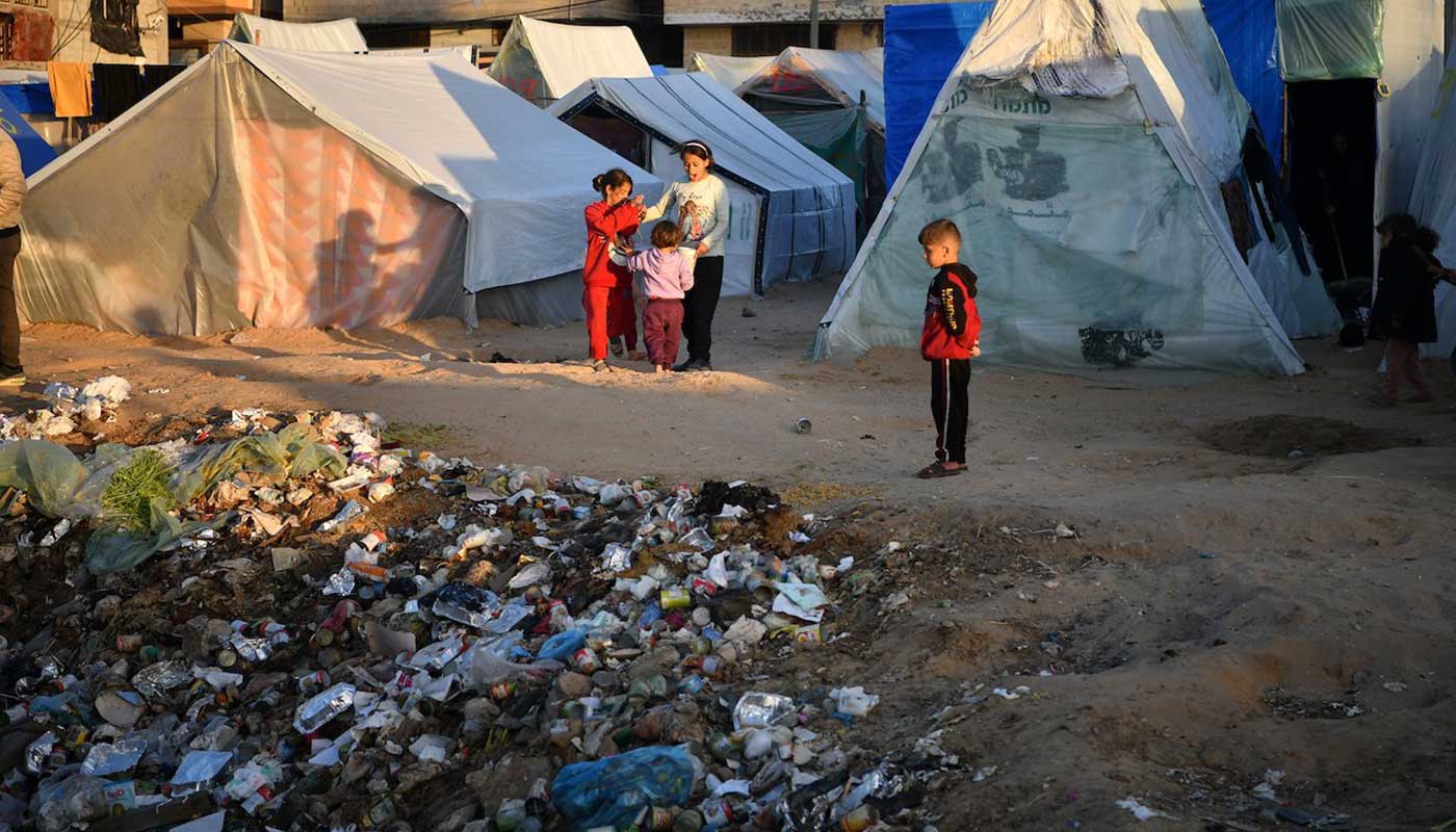 Des enfants jouent dans un camp de déplacés près d'une pile de décombres et déchets solides
