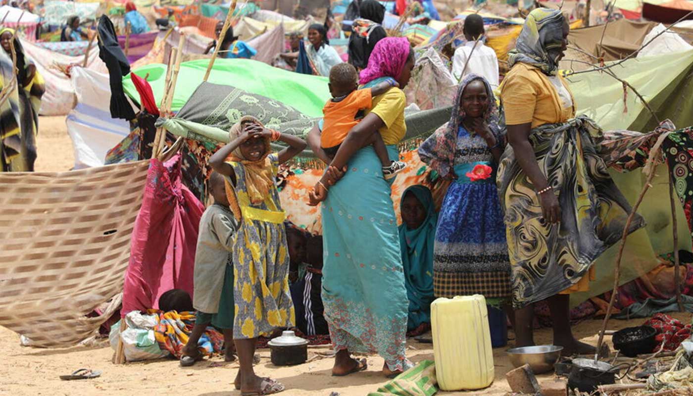 Un camp de réfugiés soudanais avec des femmes en premier plan portant des vêtements colorés