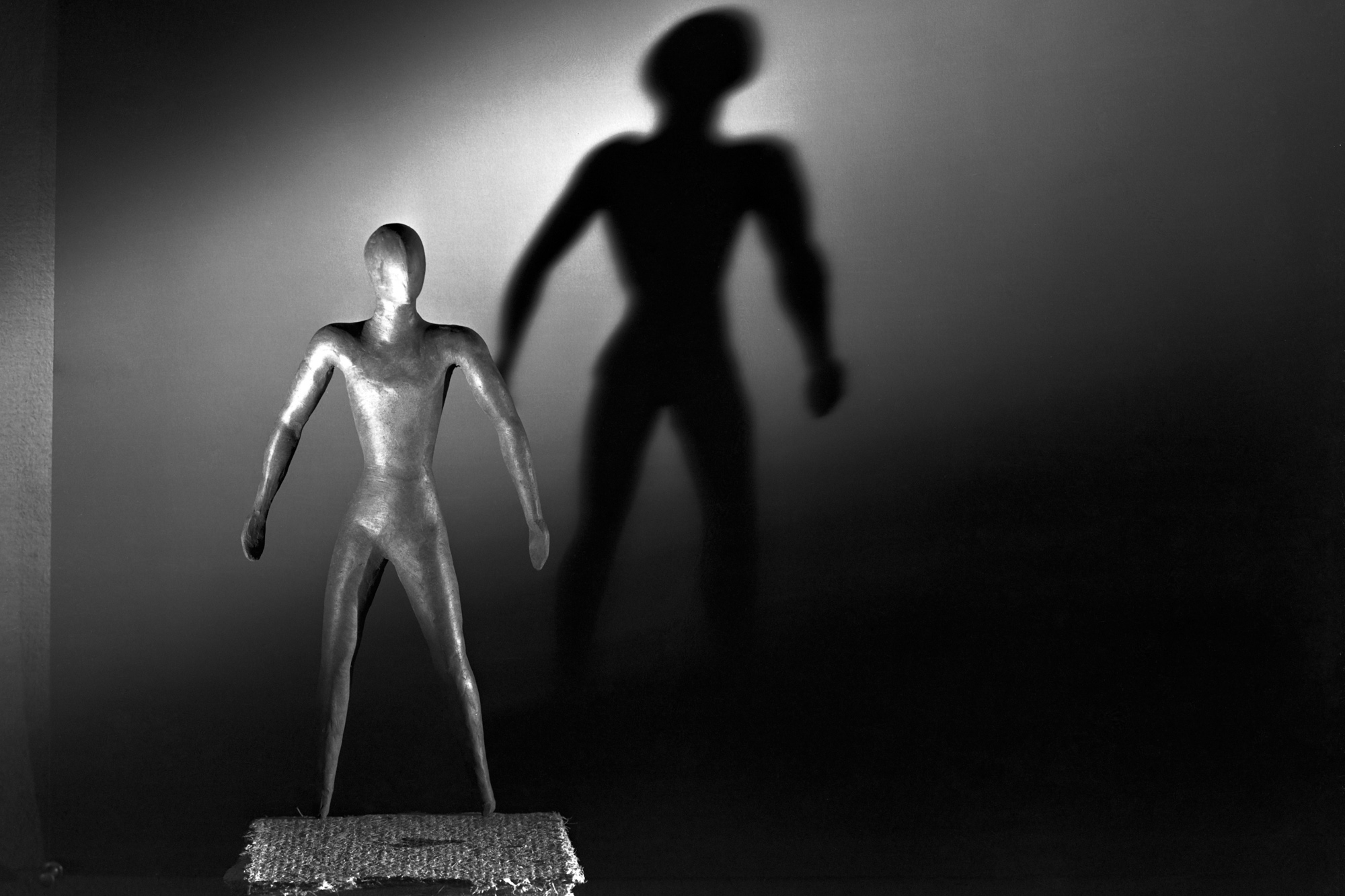 Black and white image of a human-shaped sculpture illuminated from the right side.