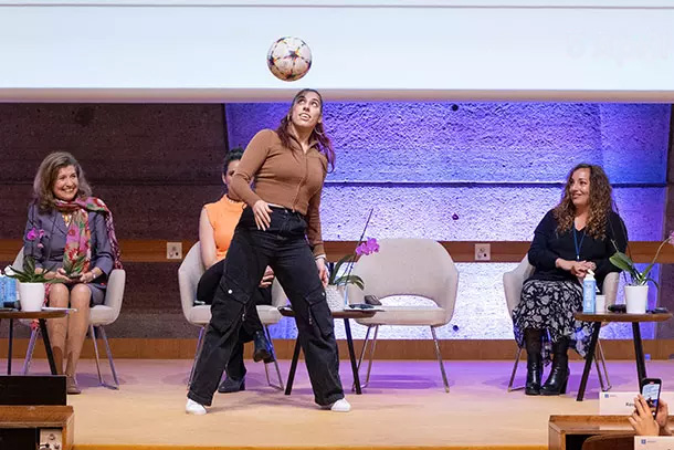 Des sportives interviennent dans une conférence, l'une d'entre elle joue avec un ballon de football