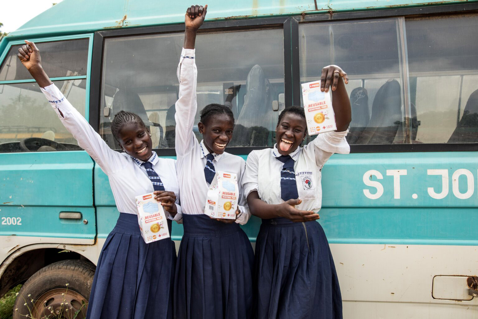 smiling schoolgirls holding up packets