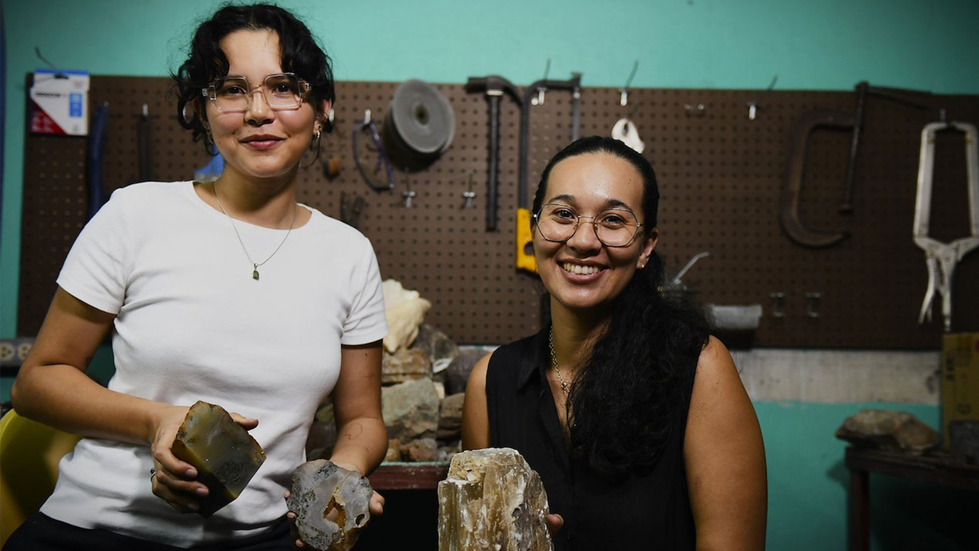Deux jeunes femmes sourient à la caméra en tenant entre les mains des minéraux précieux