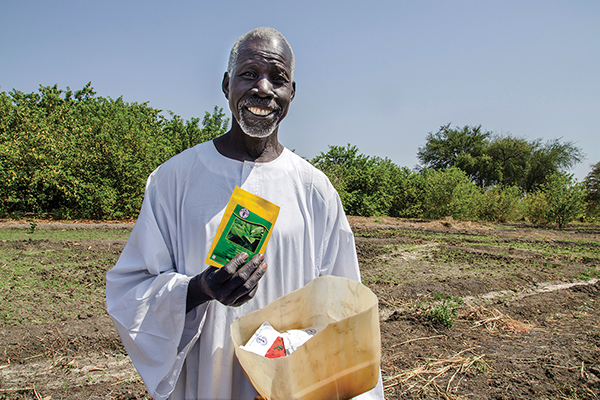 An elderly farmer in South Sudan, rebuilding homes after an emergency, holds seeds distributed by the FAO. Credit: ©FAO/Lieke Visser