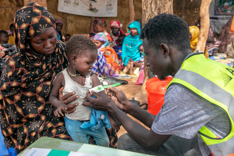 Un humanitaire mesurant le tour de bras d'un enfant en bas âge dans les bras de sa mère