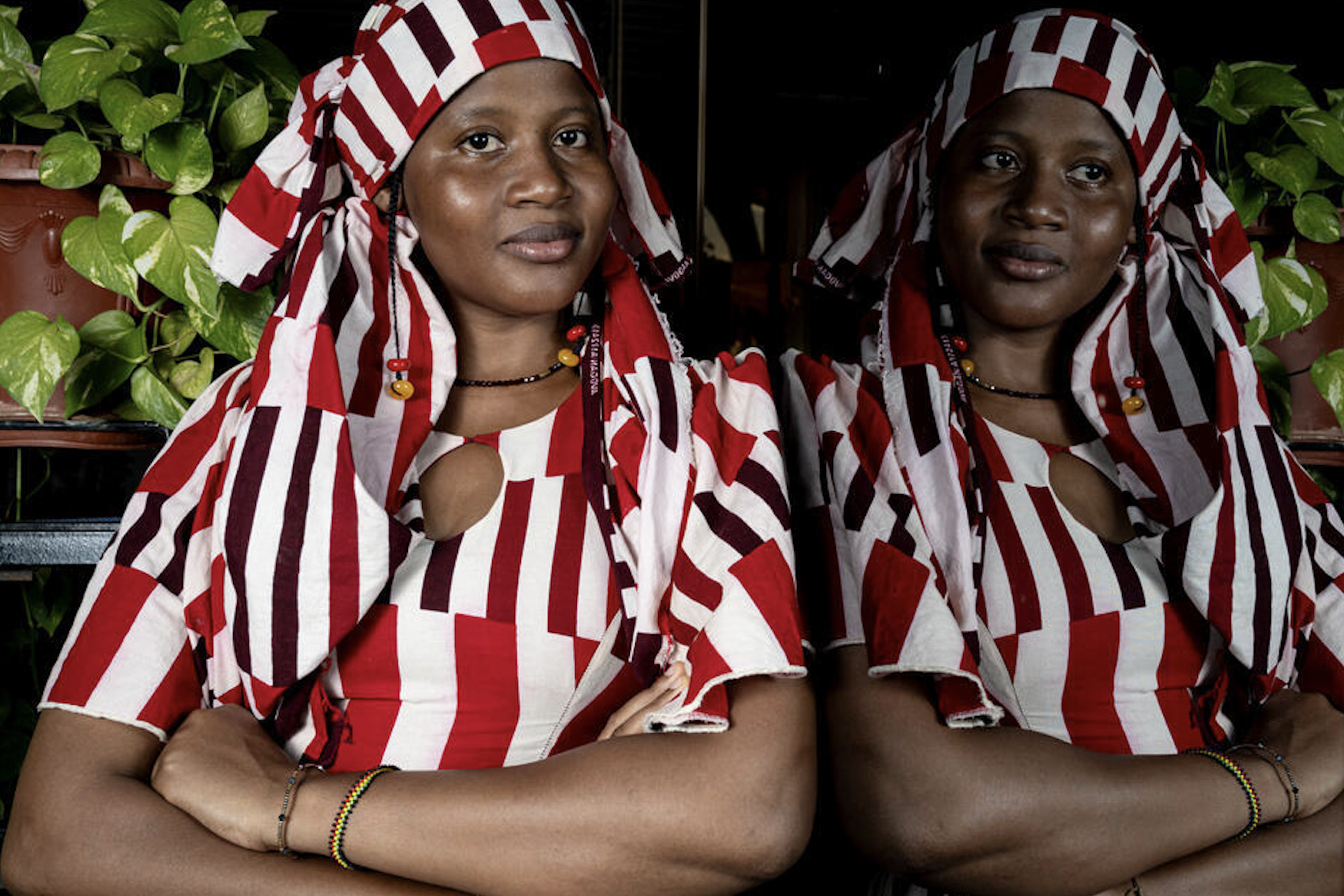 A photograph showing two women in vibrant red and white striped clothing looking into the camera